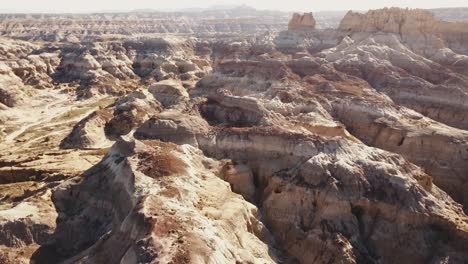 drone-shot-flying-over-while-the-camera-slowly-tilts-down-over-a-desert-moonlike-landscape,-somewhere-in-the-west-of-the-USA-in-4k