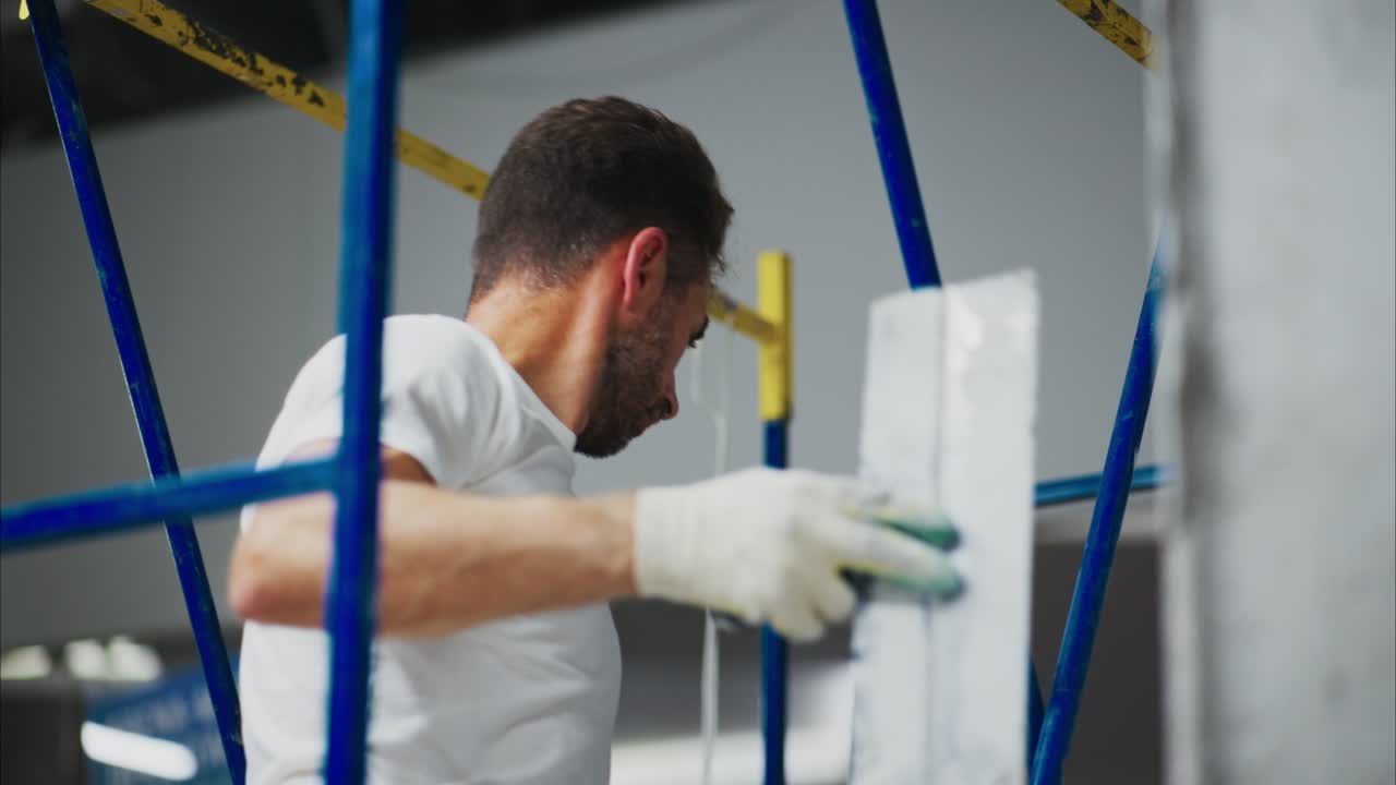 Construction Worker Performing Finishing Touches on a Wall While Utilizing a Scaffolding Setup to Ensure Safety and Precision in a Renovation Project