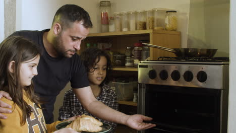 focused dad preheating food in oven with kids.