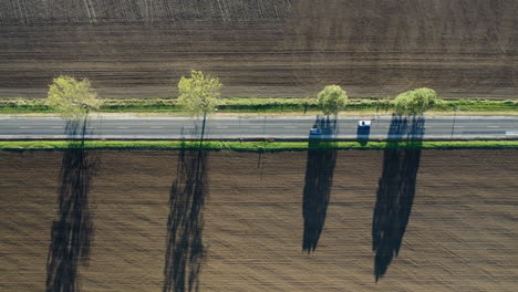 Schöne-Straße-Von-Oben-Gefilmt-Mit-Schatten-Von-Den-Bäumen-Auf-Dem-Ackerland