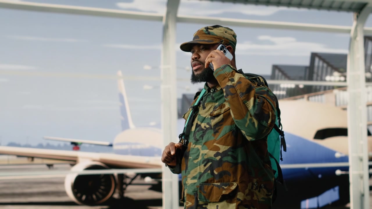 Army soldier doing mobile phone call in airport, preparing for homecoming