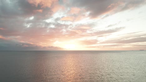 epic sunset over pacific ocean, flying backwards over open sea during sundown