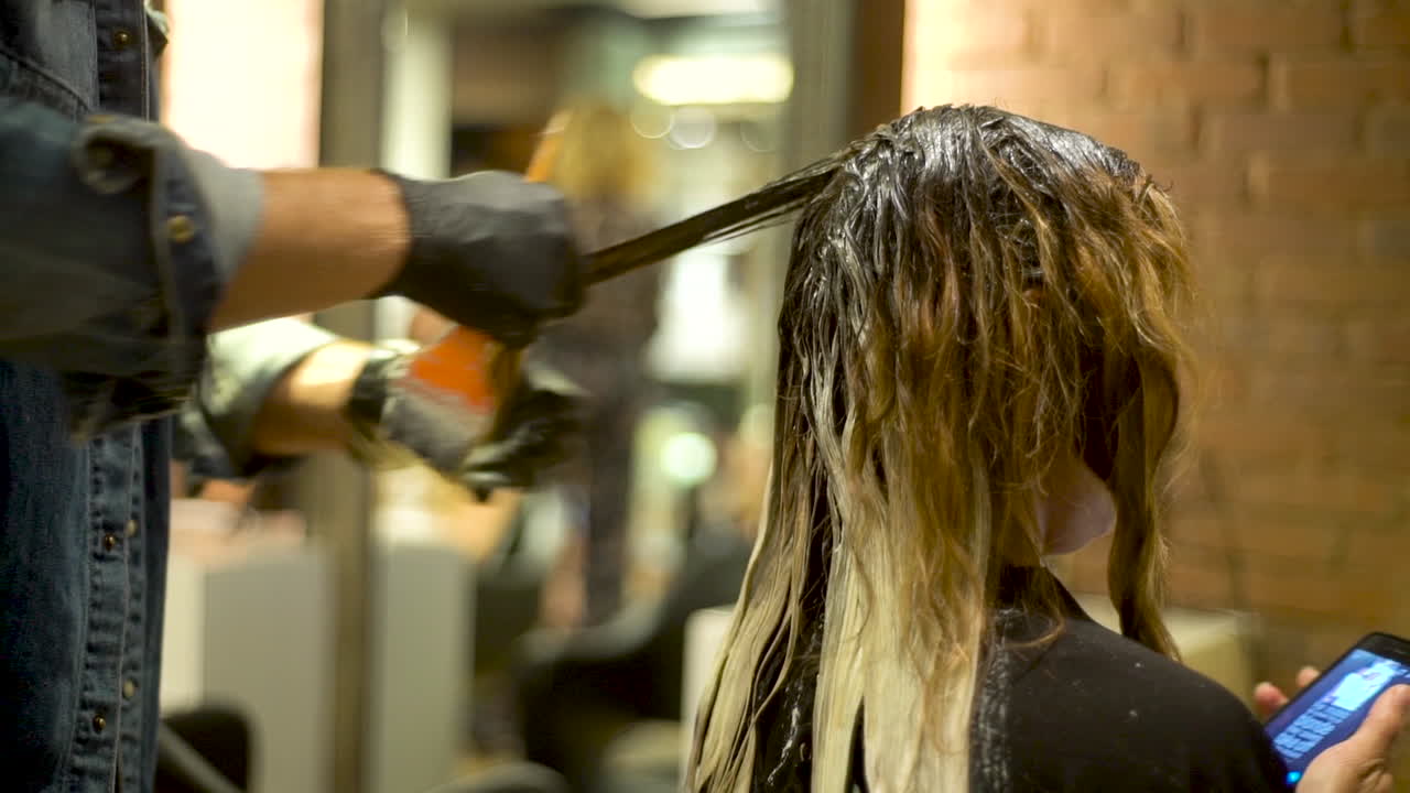 Parrucchiere professionista che esegue su una modella un trattamento per capelli.
