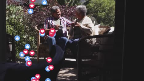 Multiple-heart-and-thumbs-up-icons-floating-against-african-american-couple-drinking-coffee-together