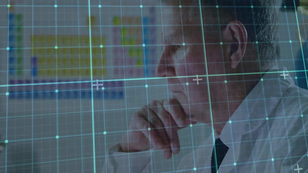 Senior male medic typing, pausing, resting chin while analyzing heatmap with teal HUD on screen