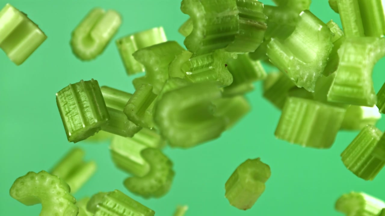 Chopped Celery Falling in Slow Motion on Green Background
