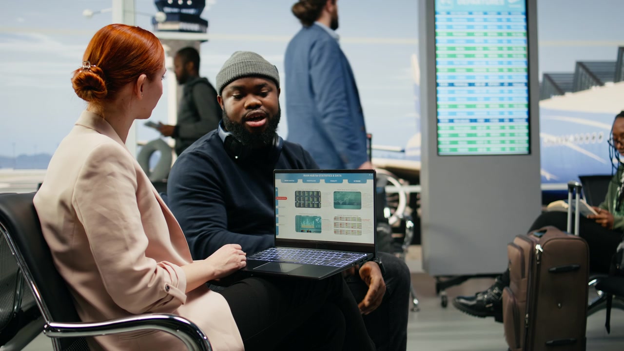 Diverse coworkers reviewing data reports on laptop in business lounge