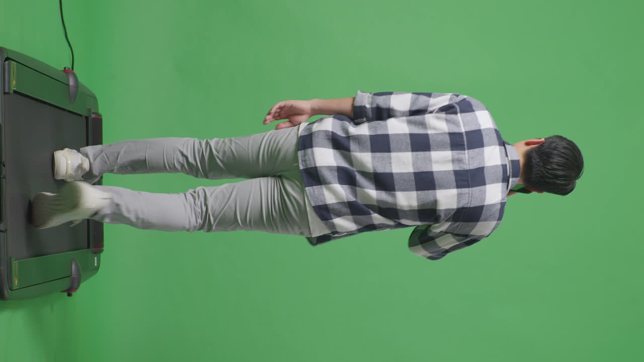 스튜디오에서 녹색 화면에서 는 동안 휴대 전화로 이야기하는 아시아 남자의 전체 몸을 뒤로 보십시오.