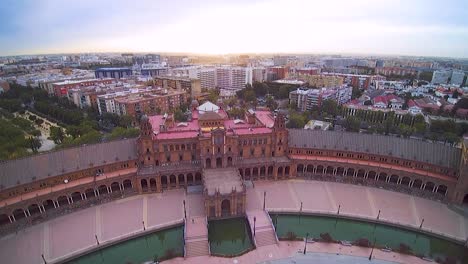 tiro de drone de plaza de españa en sevilla volando hacia el sol naciente, salida del sol, verano, sol