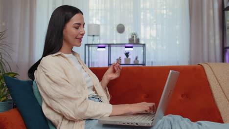 mujer joven usando tarjeta de crédito y computadora portátil, transfiriendo dinero, comprando compras en línea