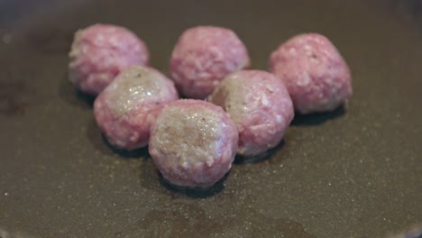 Close-up-shot-of-a-selection-of-raw-meatballs-being-cooked-in-a-pan