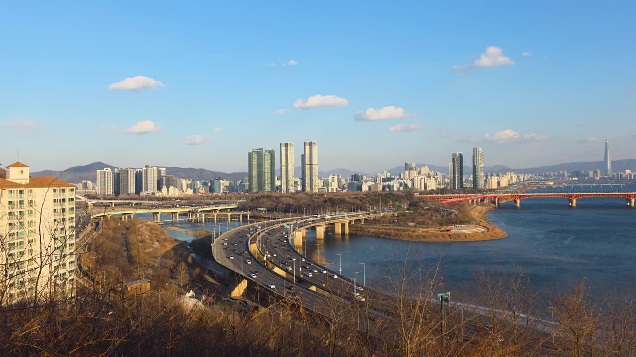 Veduta aerea dalla collina Dalmaji che domina il traffico della superstrada curva Gangbyeonbuk-ro, i ponti del fiume Han e lo skyline di Seul in una soleggiata giornata invernale