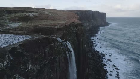 kilt rock and mealt falls in scotland with snow patches, cliffside and sea, aerial view