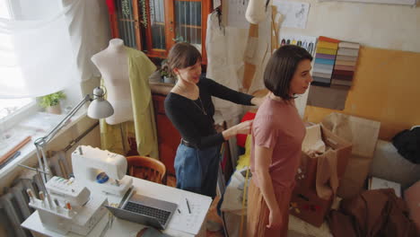 female dressmaker measuring client with tape