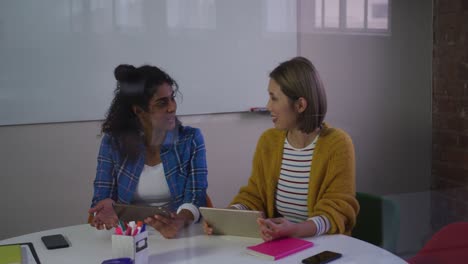 Diverse-female-business-colleagues-in-discussion-at-work-using-digital-tablets