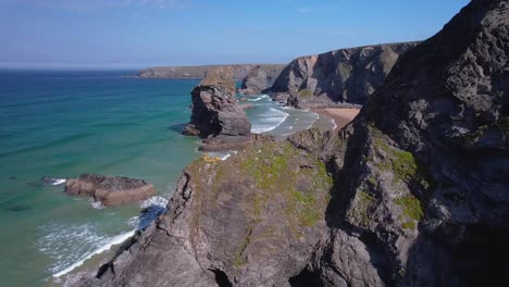 bedruthan steps aerial drone over rocky cliffs with turquoise waters on a summers day in cornwall, england, uk