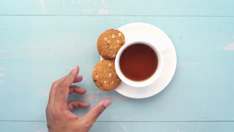 mano sosteniendo una taza de té con galletas de avena