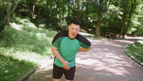 young adult asian runner suffering from back pain sports injury muscle spasm after exercise in park