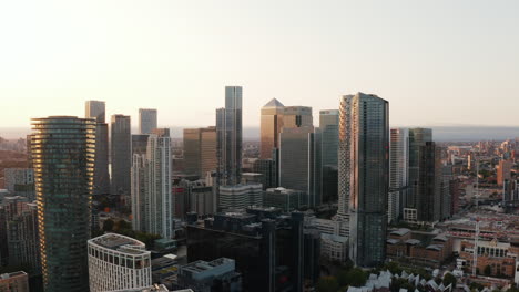 Aufsteigender-Schuss-Von-Hohen-Bürogebäuden-Im-Geschäftszentrum-Canary-Wharf.-Beleuchtet-Von-Der-Seite-Durch-Die-Untergehende-Sonne.-Wolkenkratzer-In-Der-Goldenen-Stunde.-London,-Vereinigtes-Königreich