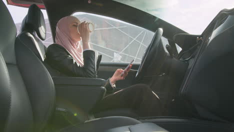 woman in hijab driving and using phone