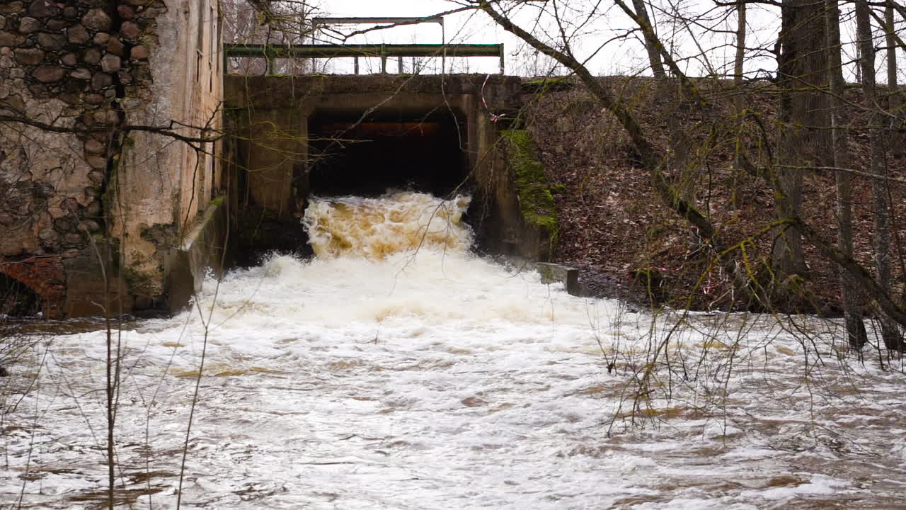 Strong waterfall current flowing through sluice in slow motion, wide shot
