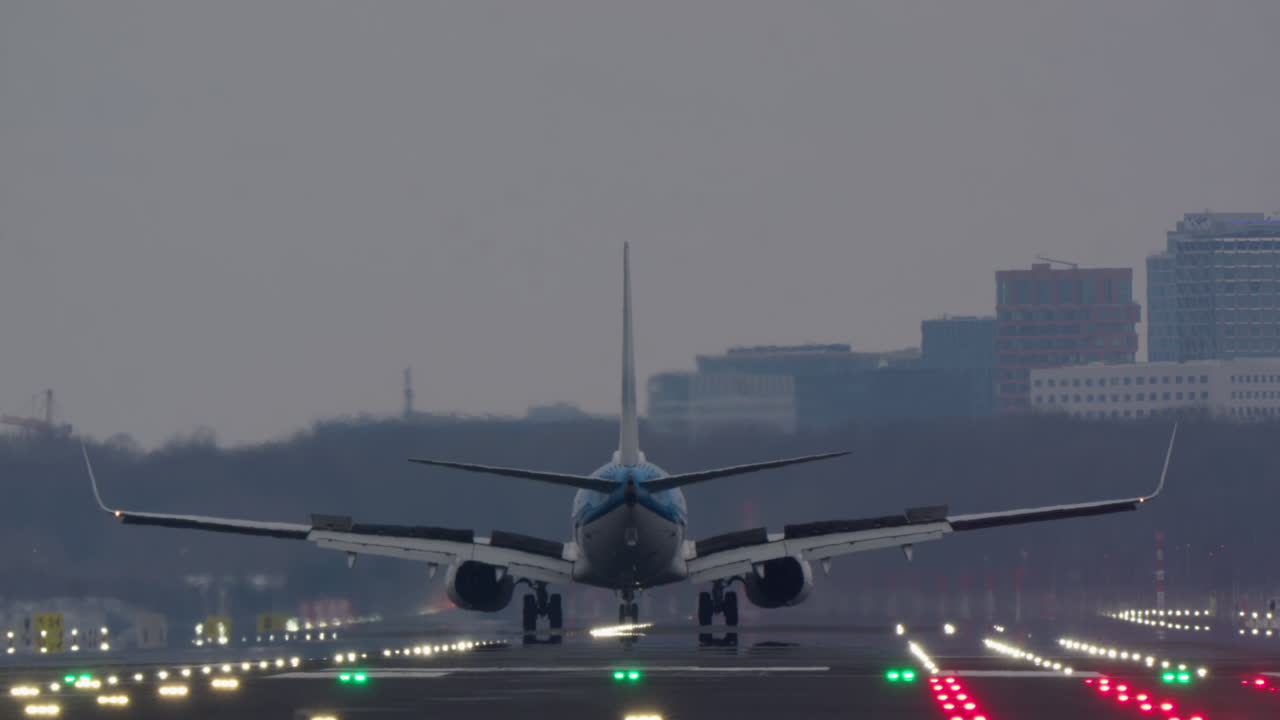 Grande aereo passeggeri in atterraggio su pista illuminata al crepuscolo.