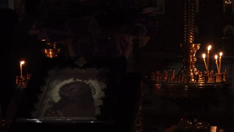 las velas encendidas parpadean junto a una pintura cristiana ortodoxa que representa a jesucristo