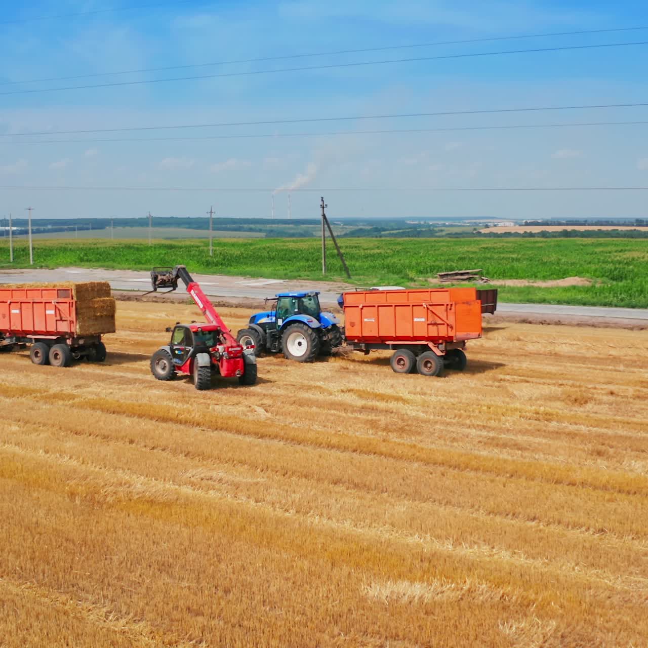 Picking bales of wheat hay at the agricultural field. Machines at farmlands work to pick up the straw left after mowing the bread