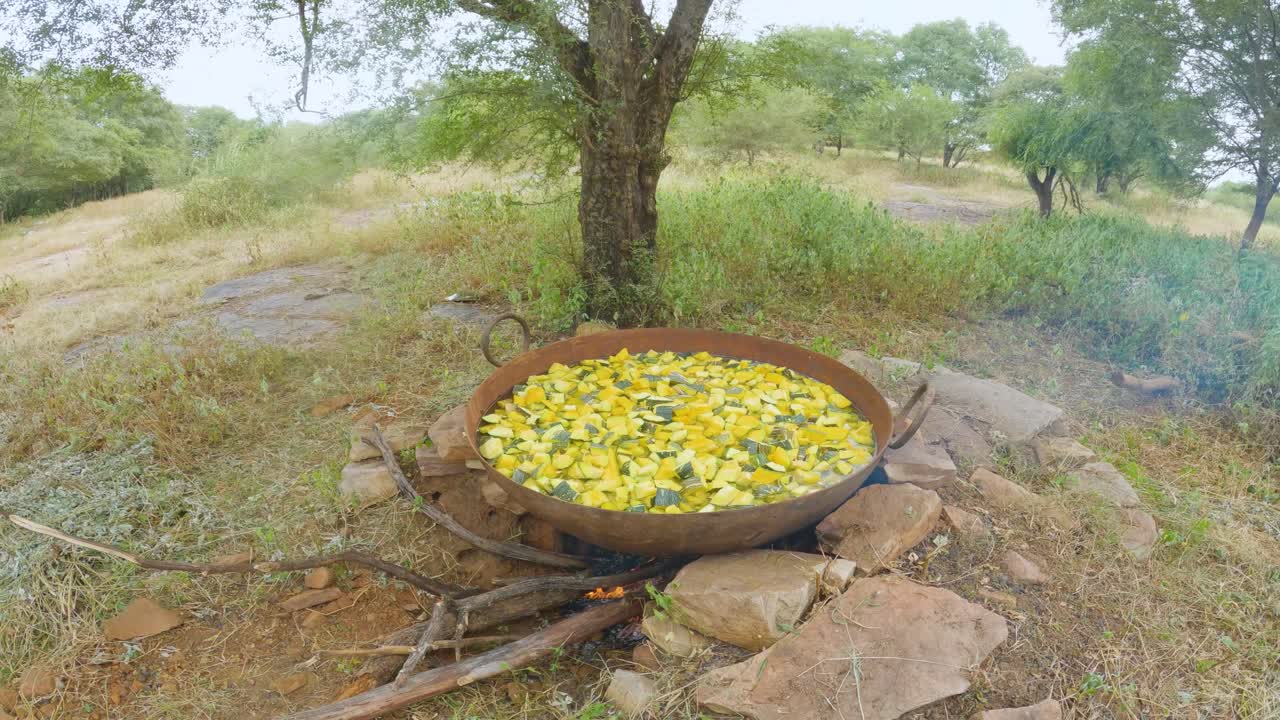 toma amplia de cocinar verduras de calabaza picadas en una olla grande en condiciones al aire libre durante un festival local de bhandara en la india rural
