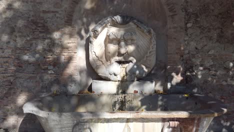 Fuente-Monumental-Llamada-Fontana-Del-Mascherone-Di-Santa-Sabina-Ubicada-En-Roma,-Cámara-Lenta-Con-Movimiento-De-Muñeca-Hacia-Adelante