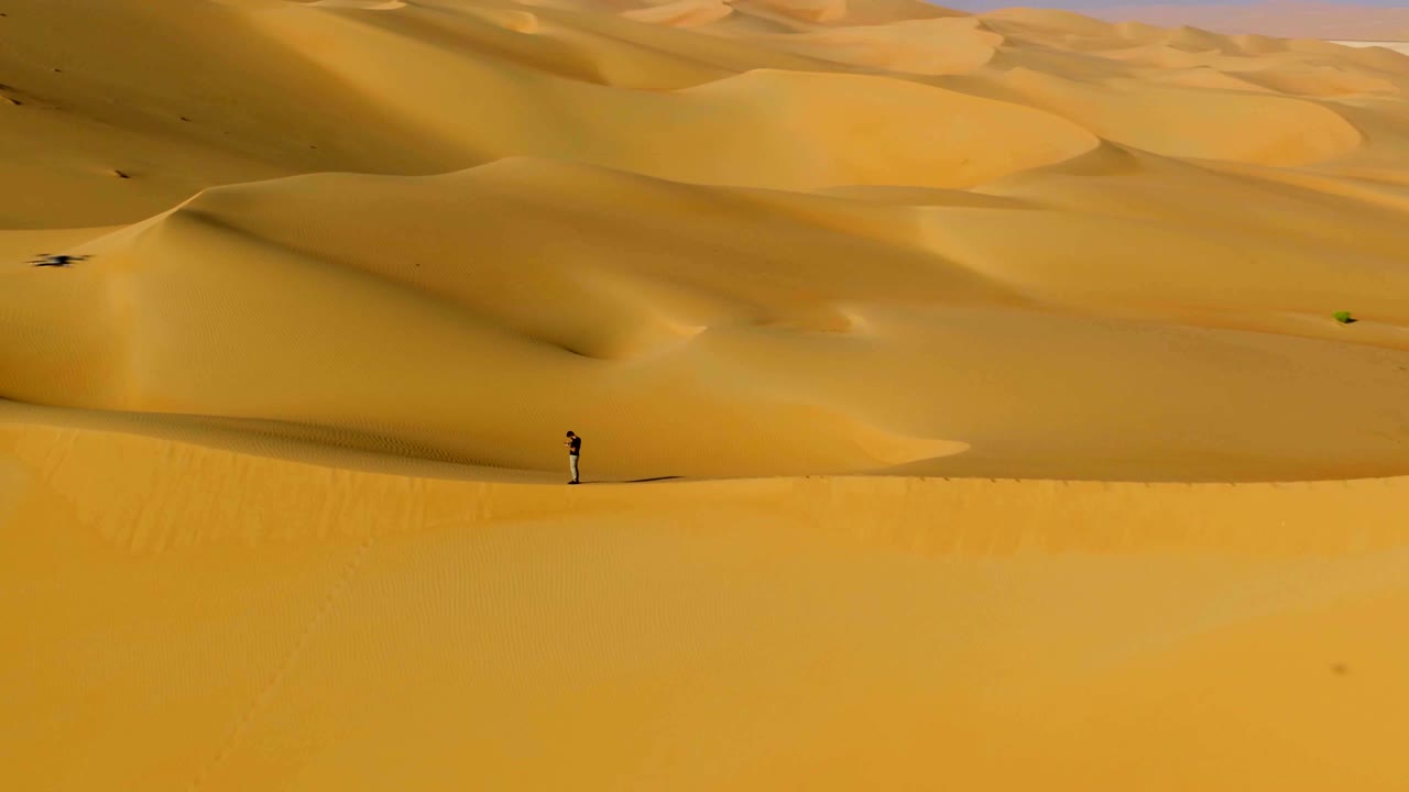 vista aérea de un hombre de pie en el borde de las dunas, u.a.e.