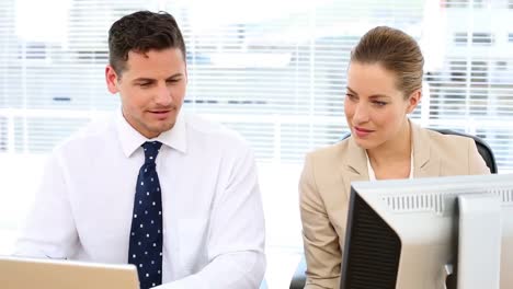 happy business team looking at computer screen together and talking at desk