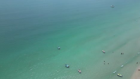 Toma-Aérea-De-La-Playa-Con-Pocas-Personas-Y-Barcos-Cerca-De-La-Costa