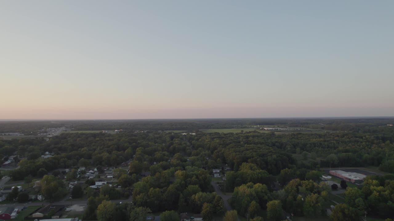 Drone hovering at a great height and capturing the whole area which include small town surrounded by tree