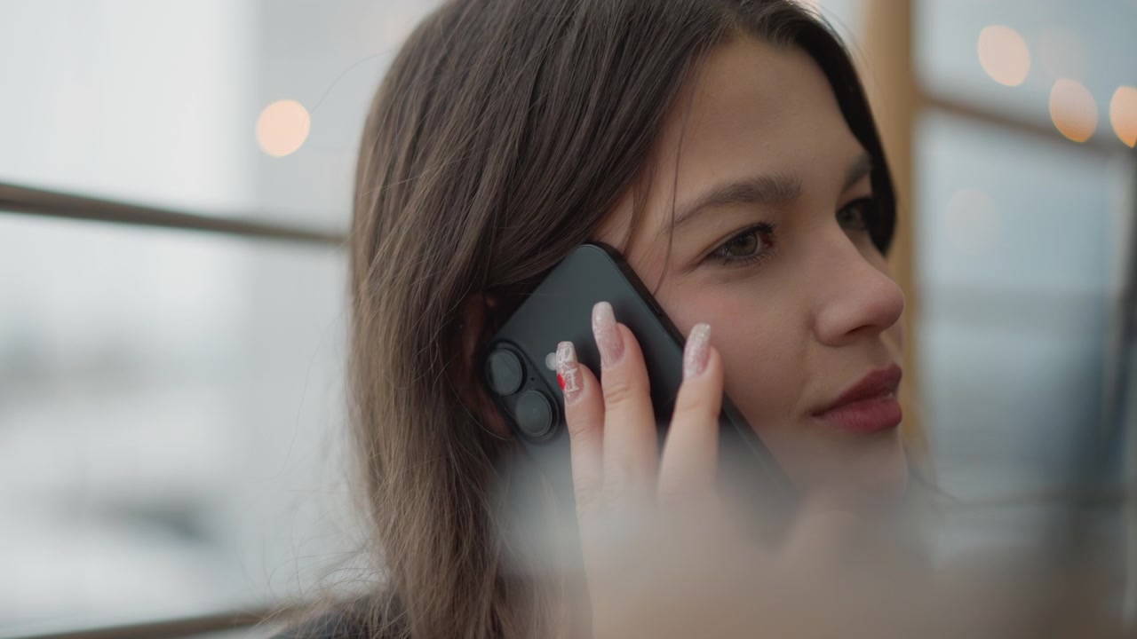 Close-up of young woman holding smartphone to ear during private indoor conversation, moving from focused listening with slight head tilt and furrowed brow to calmer pause with eyes closed beside