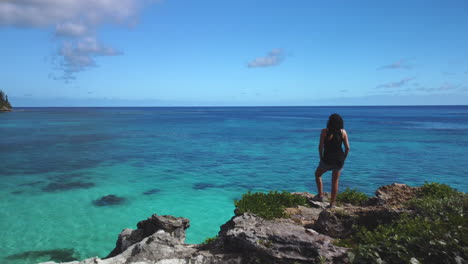 Aerial-dolly-forward-past-woman-admiring-Pacific-Ocean-view-from-Maré-Island