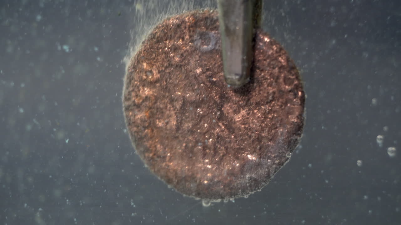 Ancient Roman coin is cleaned of corrosion with electrolytic bath