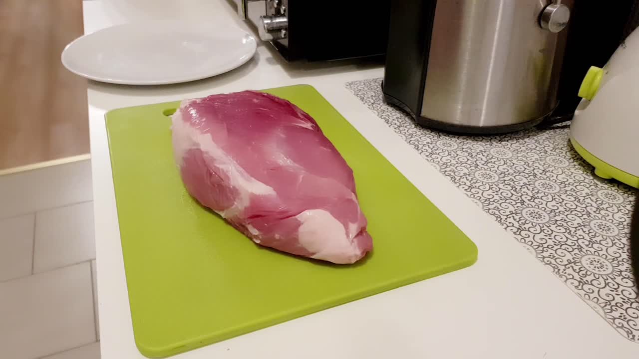 кавказская женщина разделывает свиное мясо белым ножом на зеленой доске