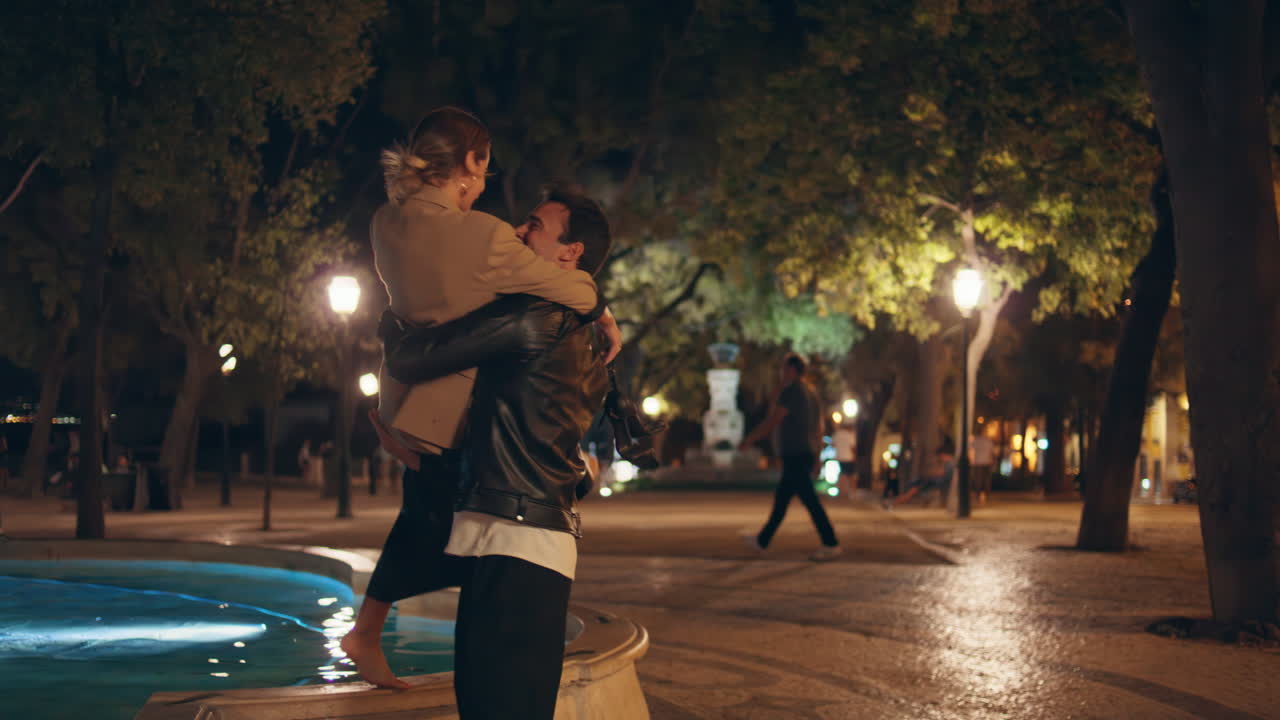 Loving couple resting city evening on date. Smiling man holding spinning woman