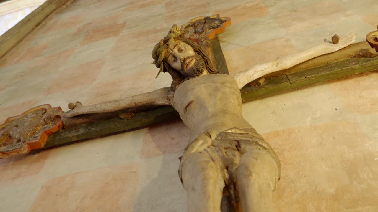 A figure of Jesus Christ hanging on the cross, located in the chapel of a historic castle