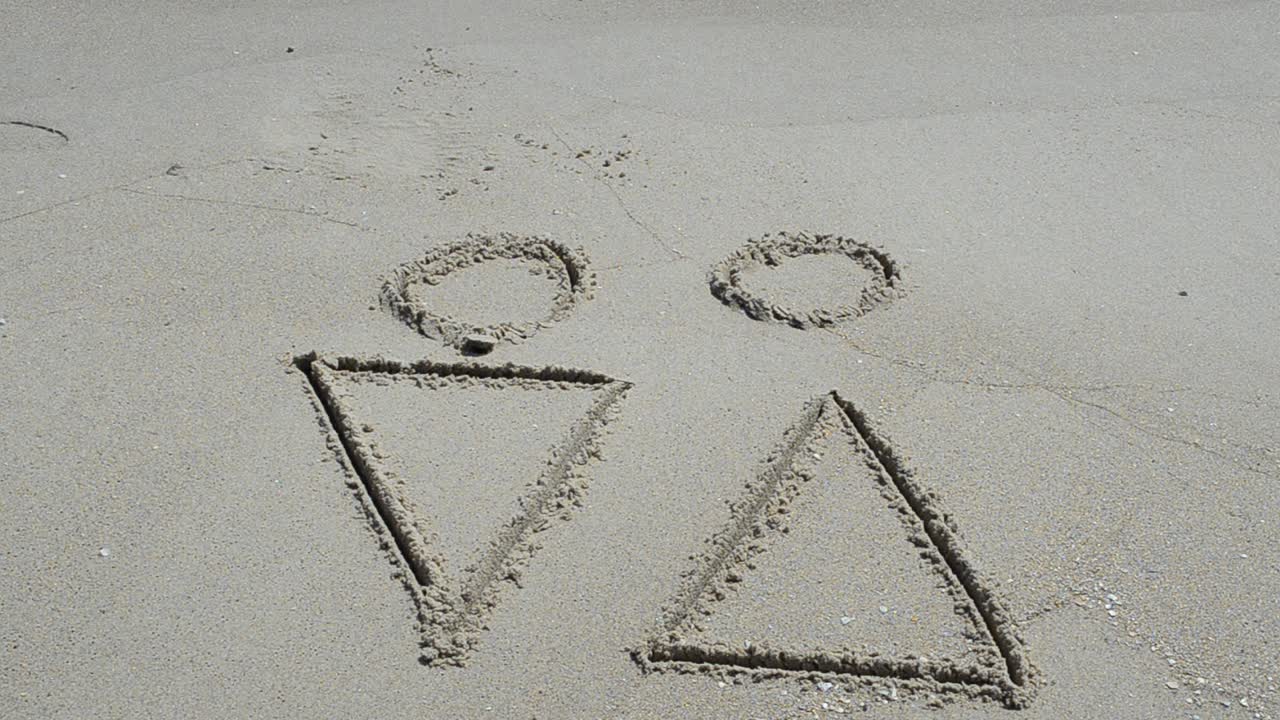 Dibujo en la arena representando el amor entre sexos opuestos. Grabación en la playa.