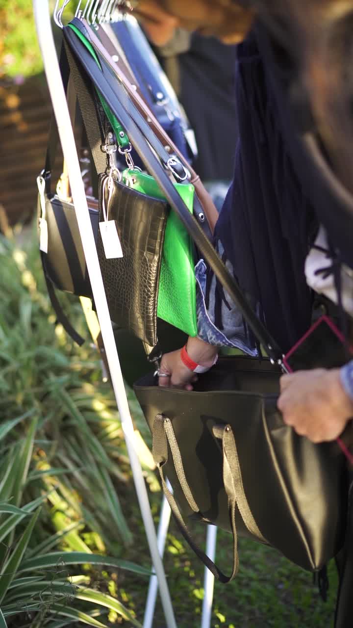 Handbag selection at the flea market, vintage fashion woman shopping, vertical video