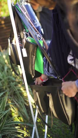 handbag selection at the flea market, vintage fashion woman shopping, vertical video