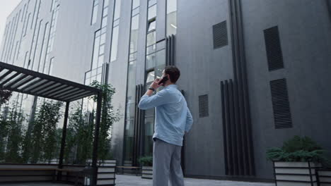 handsome man standing typing mobile phone at office district. social networking