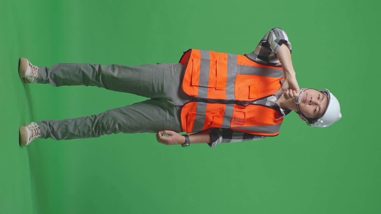 Full Body Of Asian Male Engineer With Safety Helmet Showing Thumbs Down Gesture And Shaking His Head While Standing In The Green Screen Background Studio