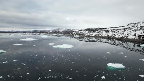 Erstaunliche-Drohnenlandschaft-In-Grönland,-Flug-über-Eisberge-Und-Spiegelung-Auf-Dem-Wasser,-Dramatischer-Himmel