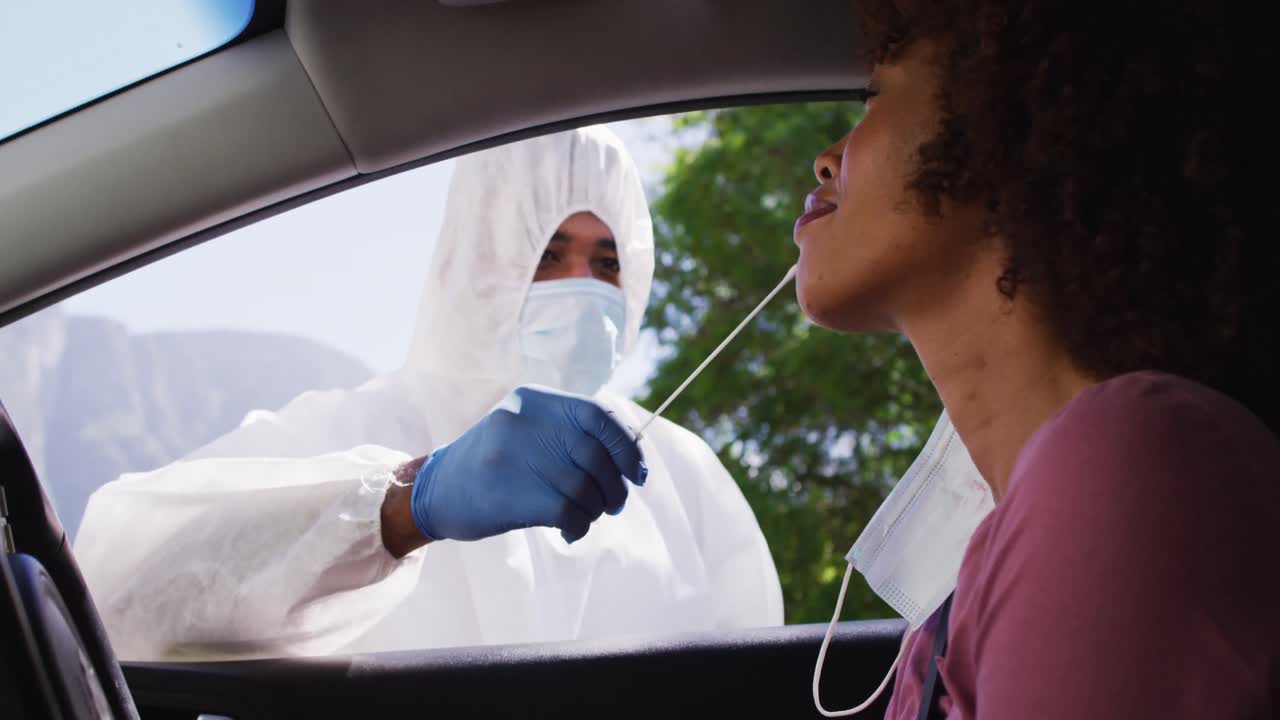 mujer afroamericana, que se hizo la prueba de covid mientras estaba sentada en el coche por un trabajador médico al aire libre