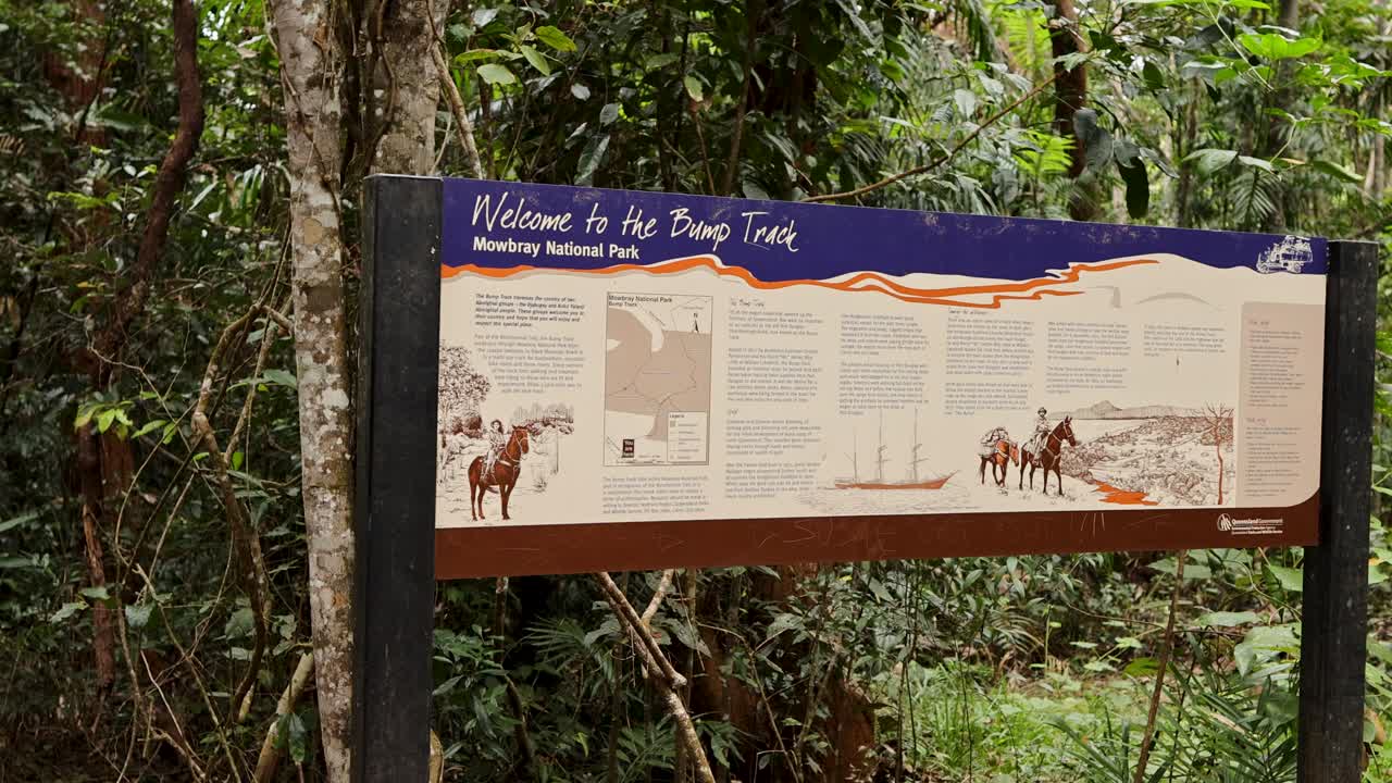 Static shot of Bump Track trail signboard surrounded by lush tropical rainforest, natural daylight