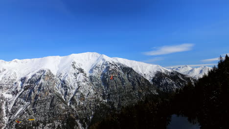 orange-rescue-helicpoter-flying-away-from-a-ski-run-in-front-of-a-beautiful-mountain-scenery