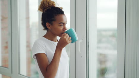 woman looking out window with coffee